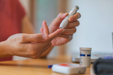 young woman using blood test kit at home while doing health check . home finger prick blood test . close up, diabetes concept, elderly health care,