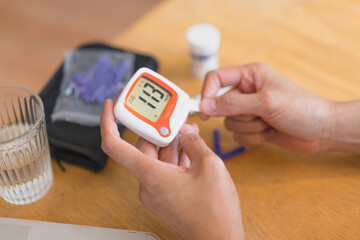 young woman using blood test kit at home while doing health check . home finger prick blood test . close up, diabetes concept, elderly health care,