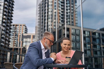 Middle-aged man and woman sit on a terrace with coffee