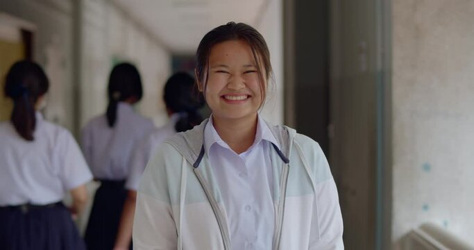 Slow motion scene of a happy smiling and laughing Asian high school student girl who is always have a fun sense of humor.
