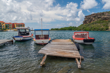 Small, colourful rowing boats, moored alongside a wooden jetty, on the Caribbean island of Curacao,...