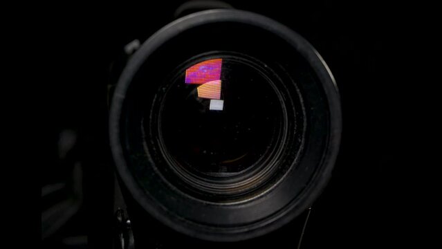 Panning the lens of a video camera with glare of light, close-up on a black background