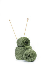 Ovillo de lana y tejido verde con agujas de madera sobre un fondo blanco liso y aislado. Vista de frente y de cerca. Copy space. Formato vertical