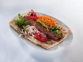 Adana kebab and garnish on pita bread