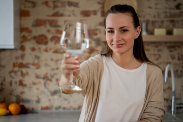 Healthy lifestyle is my choice. An active smiling woman looks into the camera, holding a glass of pure still water. A pretty woman promotes drinking water as an easy way to take care of health.