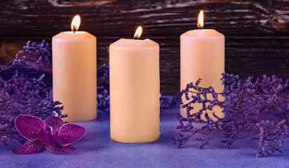 Obraz na płótnie Canvas Burning candles and purple orchid flower. Dried flowers as a decoration. Romantic composition on a dark wooden background. Aromatherapy concept