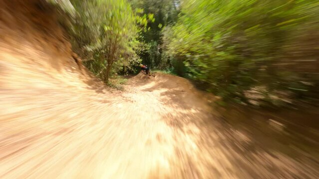Mountain-bike rider riding fast at forest Trail Pathan followed by fpv drone 