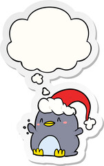 cartoon penguin wearing christmas hat and thought bubble as a printed sticker