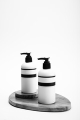 two black and white Bottles With Pump On black stone slabs on on white background