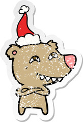 distressed sticker cartoon of a bear showing teeth wearing santa hat