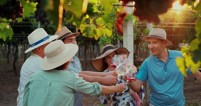 Family Toasting With Wine In Vineyards At Sunset, Fine Dining Meal Outdoors Among Vineyards In Winery