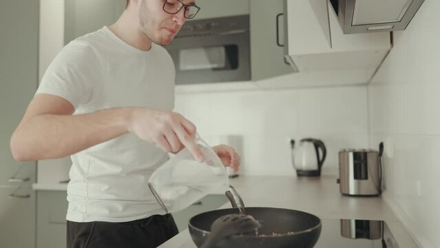 h&uuml;bscher junger Mann singt / tanzt beim kochen in einer aufger&auml;umten K&uuml;che