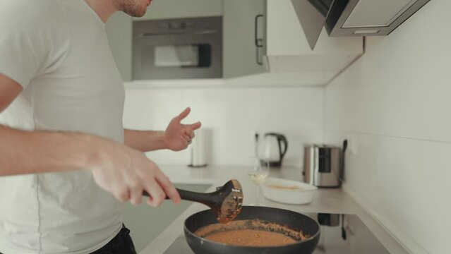 junger, h&uuml;bscher Mann tanzt beim kochen zuhause in der K&uuml;che