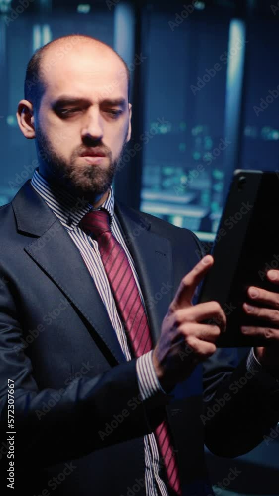Poster vertical video: datacenter engineer looking at mainframe diagnostics using digital tablet, inspectin