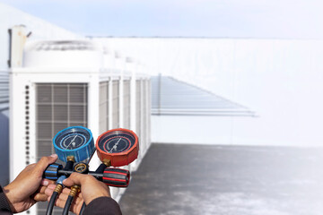 Air repair mechanic using measuring equipment for filling industrial factory air conditioners.	