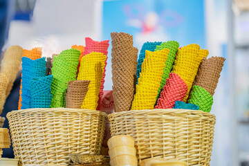 Two wicker baskets with multi-colored wafer cornets for different tastes of ice cream. Real scene...