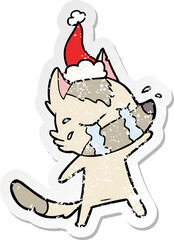 distressed sticker cartoon of a crying wolf wearing santa hat