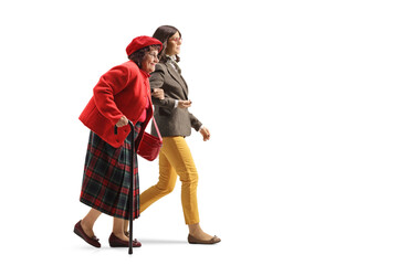 Young woman holding an older woman under arm and walking together