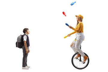 Boy standing and watching a female riding a mono cycle and juggling