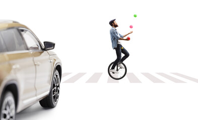 Street artist juggling and riding a mono cycle on a pedestrian crossing