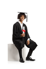 Male african american graduate student in a gown sitting and holding a diploma