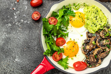 Closeup of tasty fried eggs with avocado and mushrooms. Ketogenic diet. Low carb high fat breakfast. Healthy food concept. place for text, top view.