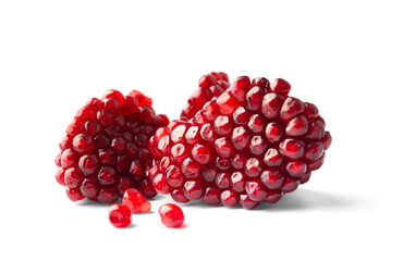 Two pieces of pomegranate and a few scattered seeds on a white background