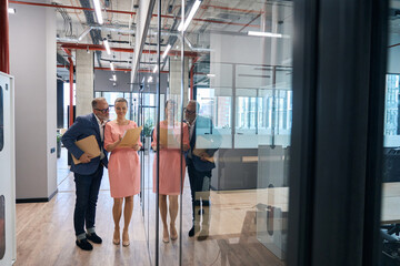 Couple employees business company looking through documents in office corridor