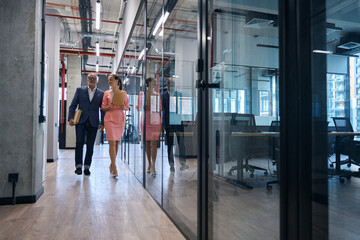 Couple of employees business company walk along corridor office building