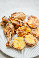 Chicken baked in pieces with potatoes and onion on a white dish. Home cooking. Healthy food, cooked without oil and salt.