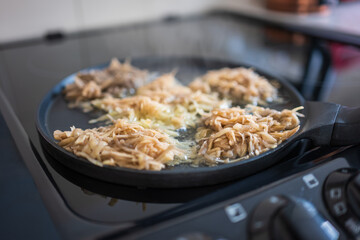 Frying crepe pancake pan with gratet potato on hot cooker hob