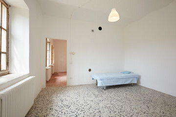 Bedroom with sigle bed in old country house with white walls