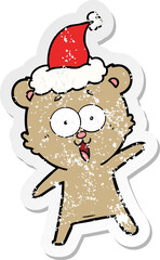 laughing teddy  bear distressed sticker cartoon of a wearing santa hat