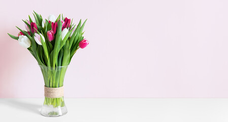 Colorful spring tulips in a vase on a white table.