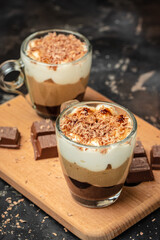 three chocolate in a glass jar decorated with mint on a dark background. Layered delicious dessert. vertical image. place for text