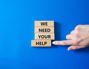 We need your help symbol. Wooden blocks with words We need your help. Businessman hand. Beautiful blue background. Business and We need your help concept. Copy space.