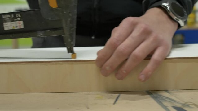 Motion shot of a tacker nail gun tool shooting on wood by an carpenter hands