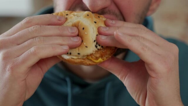 Close-up Of A Young Man Greedily Eating A Delicious Hamburger, Feeling Very Hungry, Consuming Fast Food