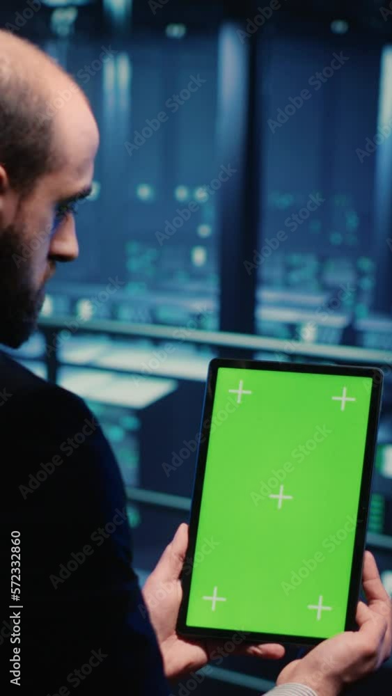 Poster vertical video: network engineer doing system check on green screen, using tablet showing chroma key