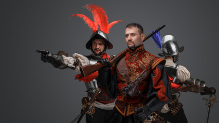 Studio shot of handsome conquistador with rifles and two soldiers dressed in plate armor.
