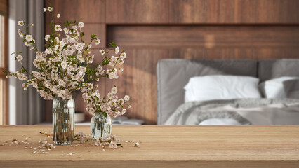Wooden table, desk or shelf close up with branches of cherry blossoms in glass vase over wooden...