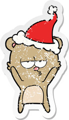 bored bear distressed sticker cartoon of a wearing santa hat