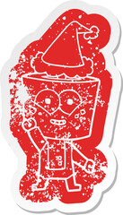 happy cartoon distressed sticker of a robot waving hello wearing santa hat