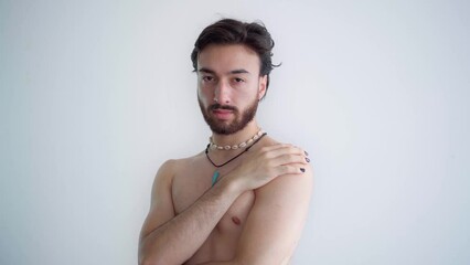 Young queer latin gay shirtless man looking at camera and hugging himself. Video 4k.