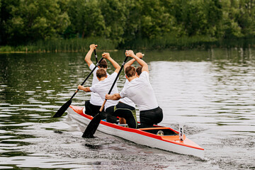 four man athletes canoeist paddling in canoe on lake