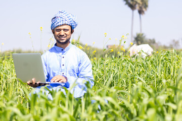 Young farmer with Laptop - obrazy, fototapety, plakaty