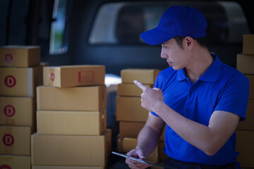 Deliver service. Man With Box in Car Outdoors Delivery Man in uniform holds parcel and phone car outdoors Delivery man taking parcels from The Delivery service