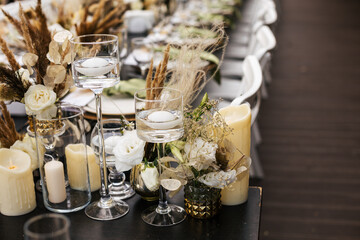 Wedding decorations.Close up of  decorative composition for wedding table with fresh and dried flowers, candles and and light bulbs. Celebration details, wedding outdoor
