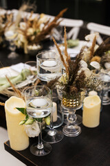 Wedding decorations.Close up of  decorative composition for wedding table with fresh and dried flowers, candles and and light bulbs. Celebration details, wedding outdoor
