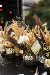Wedding decorations.Close up of  decorative composition for wedding table with fresh and dried flowers, candles and and light bulbs. Celebration details, wedding outdoor

